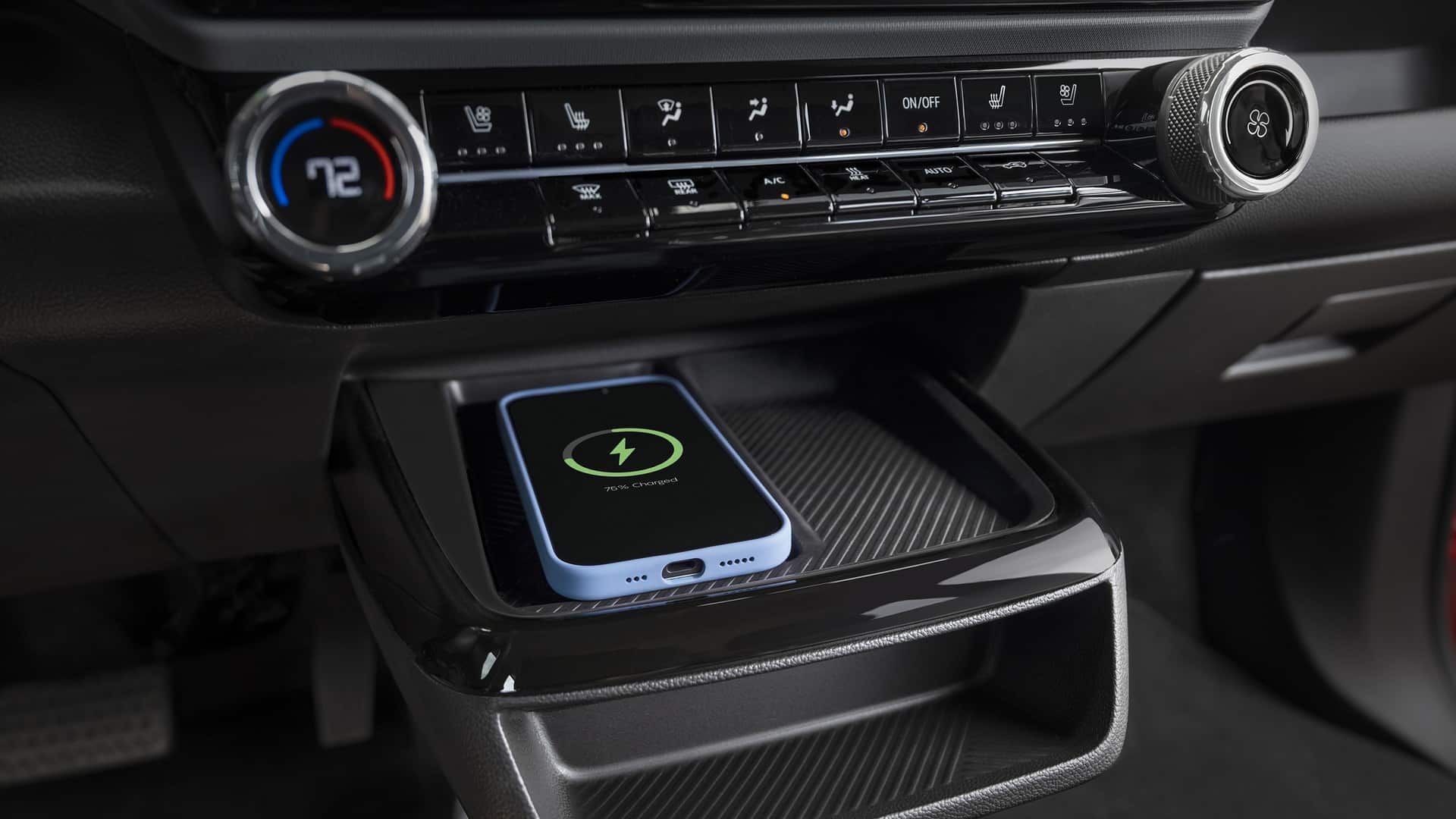 Wireless phone charging tray in a car with climate controls above, displaying 76% charge.