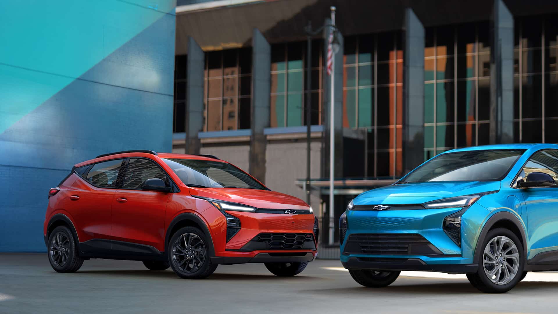 Red and blue electric SUVs parked in an urban setting, showcasing modern design.