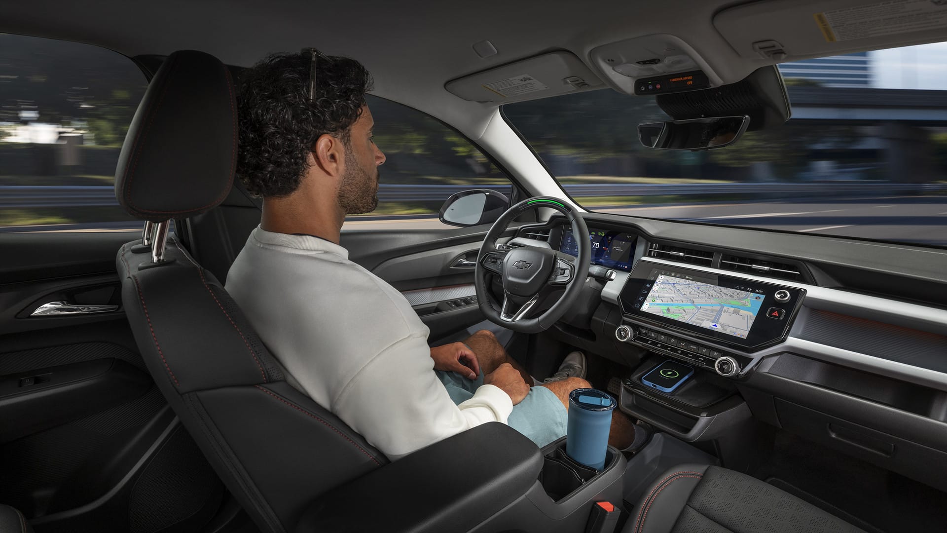 Man relaxing in a Chevrolet with autonomous driving, navigating via touchscreen display.