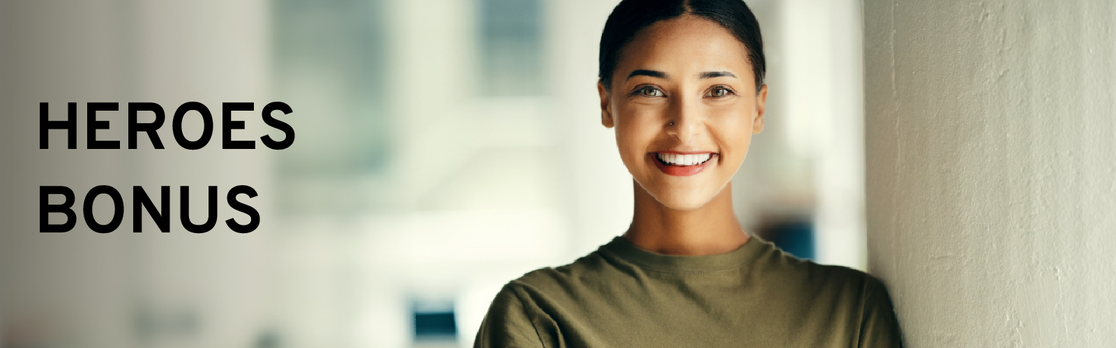 Smiling person in a green shirt next to "Heroes Bonus" text, with blurred background.