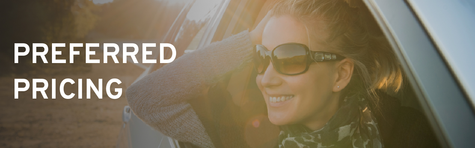 Smiling woman wearing sunglasses leans out car window, text reads "Preferred Pricing," sunlit background.