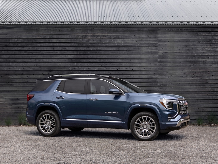 Red SUV with a sleek design parked indoors. The vehicle has prominent headlights and a bold front grille. The setting features a modern and spacious environment with architectural elements in the background.