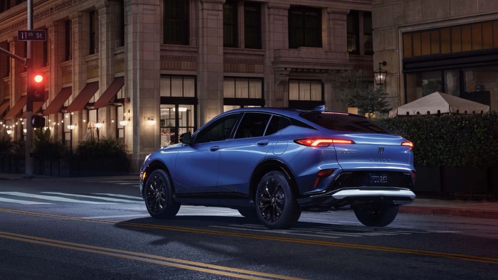 Blue SUV parked on a city street at night near a historic building with soft lighting.